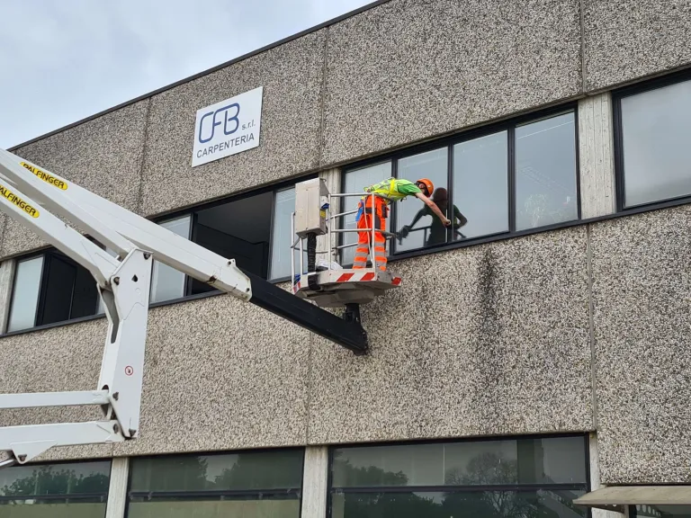 Operatore CEGS su piattaforma aerea pulisce la facciata di una palazzina uffici