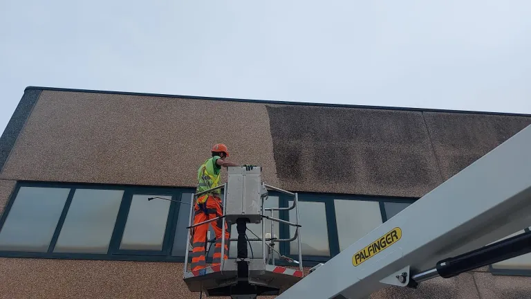 Operatore CEGS su piattaforma aerea durante la pulizia della facciata di un edificio
