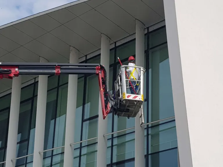 Operatore CEGS nel cestello di una piattaforma pulisce le vetrate di un edificio